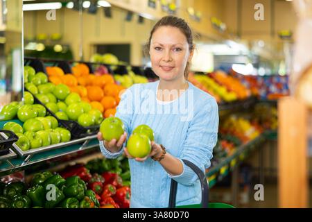 Die Frau wählt Äpfel im Bauernladen Stockfoto