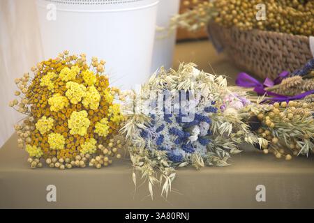 Nahaufnahme lebendiger, getrockneter Blumensträuße in Gelb-, weiß- und Blautönen, die ein rustikales und charmantes Blumenarrangement schaffen. Stockfoto
