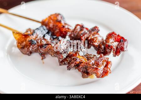 Saftige und geschmackvolle Grillspieße aus Schweinefleisch werden auf einem weißen Teller in einem lokalen Restaurant in Roxas City, Philippinen, serviert Stockfoto