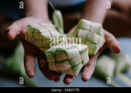 Nahaufnahme von handgemachtem Ketupat, traditionellen Reisknödeln, die in gewebte Palmblätter gehüllt sind. Wird oft während festlicher Feiern wie Eid al-Fitr genossen Stockfoto