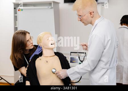 Gruppe verschiedener Medizinstudierenden, die sich mit dem Stethoskop anatomisches Modell während der Praxissitzung untersuchen Stockfoto