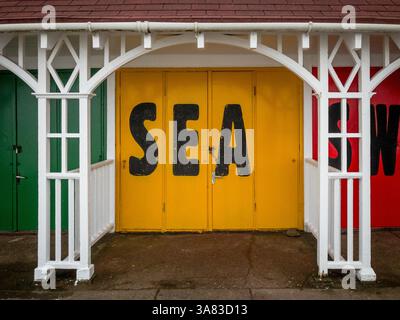 Strandchalet mit gelben Türen, die das Wort „Meer“ in schwarz lackiert haben, liegt in South Bay, Scarborough. Stockfoto
