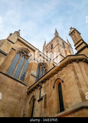 Außenaufnahme der Southwark Cathedral vom Boden aus mit Blick nach oben, mit dem historischen zentralen Turm vor einem blauen Himmel. Stockfoto