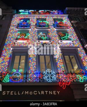Das Geschäft Stella McCartney in London ist zu Weihnachten mit leuchtenden, farbigen Lichtern beleuchtet und sorgt für eine festliche und auffällige Präsentation bei Nacht. UK Stockfoto
