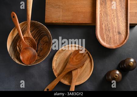 Hölzerne Küchenlöffel, Teller auf schwarzem Hintergrund Stockfoto