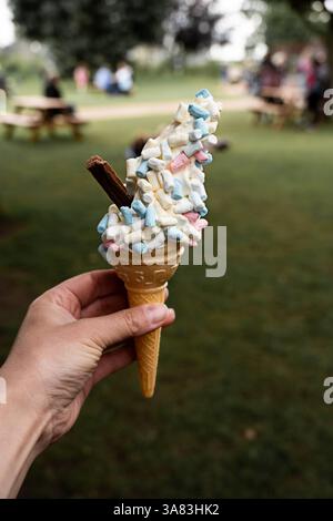 Weibliche Hand, die Eiskegel mit Marshmallow hält, Sommergenuss Stockfoto