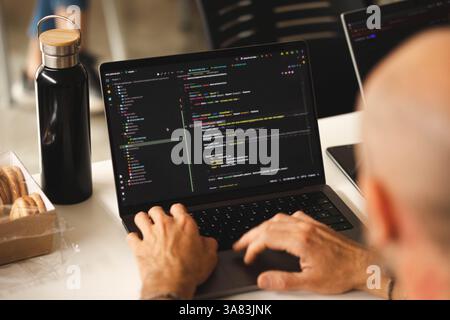 Eine Nahaufnahme eines Laptops, während die Hände eines Mannes Code schreiben Stockfoto