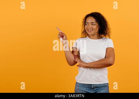 Glückliche junge afroamerikanische Frau, die mit einer Hand seitwärts zeigt Stockfoto