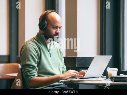 Ein Mann mit Kopfhörern arbeitet an seinem Computer Stockfoto