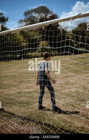 Ein Junge steht vor einem Fußballtor. Ein Blick durch das Netz Stockfoto