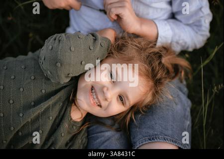 Schwester liegt auf dem Schoß ihres Bruders und schaut auf Stockfoto