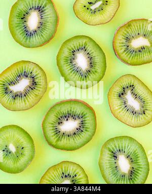 Draufsicht auf viele Scheiben Kiwis auf einem soliden grünen Hintergrund. Stockfoto