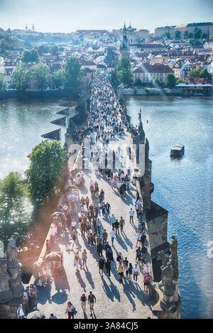 PRAG - 10. MAI 2024: Touristen wandern auf der Karlsbrücke in Prag mit Prager Burg und Moldau im Hintergrund an sonnigen Sommertagen Stockfoto