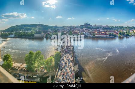 PRAG - 10. MAI 2024: Touristen wandern auf der Karlsbrücke in Prag mit Prager Burg und Moldau im Hintergrund an sonnigen Sommertagen Stockfoto