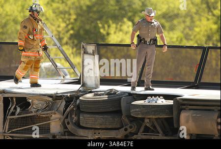 11. April 2013 - Irving, TX, USA - Texas DPS Offiziere und Feuerwehrleute inspizieren die Räder des Charterbusses, der am Donnerstag, den 11. April 2013, auf der Seite des George Bush Highway in Irving, Texas, umgekippt ist. Zwei Menschen starben bei dem Unfall, als der Bus auf den Betonmittelpunkt traf und umkippte. (Bild: © Tom Fox/MCT/ZUMAPRESS.com) Stockfoto