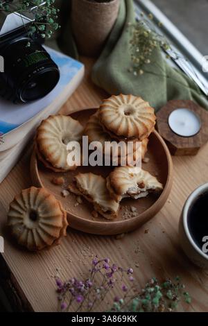 Blick von oben auf einen Stapel hausgemachter Kuchen mit Kondensmilch auf der Fensterbank mit Vintage-Kamera, Kerze und Blumen Stockfoto