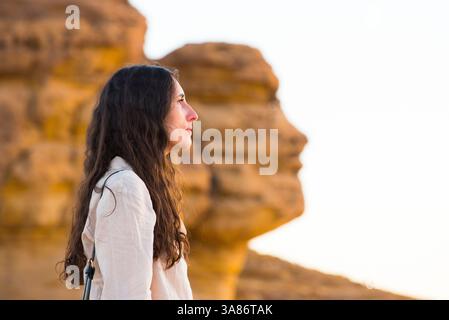 Frau vor Face Rock, eine Sandsteinformation in Form eines menschlichen Kopfprofils, Hegra, UNESCO, Alula, Provinz Medina, Saudi-Arabien Stockfoto