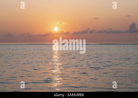 Sonnenuntergang über dem klaren Wasser der Lagune auf einer exotischen Insel auf den Malediven im Indischen Ozean Stockfoto