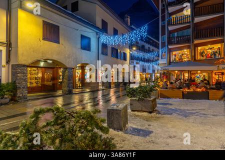 Blick auf Restaurants und Bars an der Via Roma in der Abenddämmerung, Courmayeur, Aostatal, Italien Stockfoto