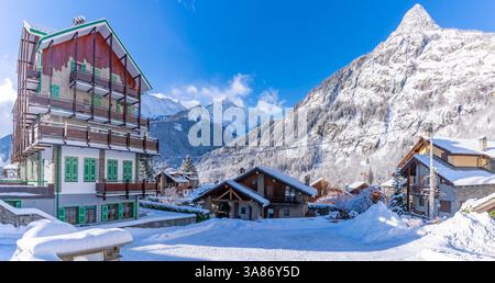 Blick auf Chalets und schneebedeckte Berge in Courmayeur bei Sonnenaufgang im Winter, Courmayeur, Aostatal, italienische Alpen, Italien Stockfoto