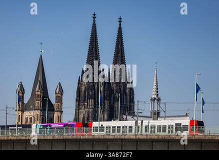 Köln, Deutschland. März 2025. Eine KVB (Kölner Verkehrsbetriebe) fährt am Dom vorbei über die Deutzer Brücke. Quelle: Oliver Berg/dpa/Alamy Live News Stockfoto