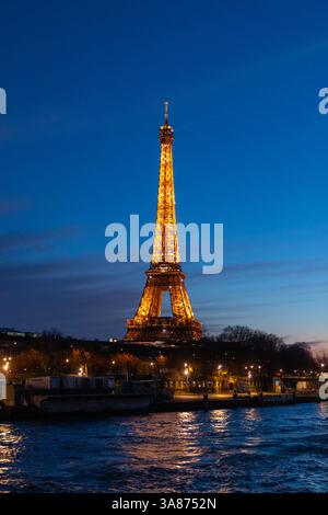Paris, Frankreich - 24. Februar 2025: Nächtlicher Blick auf den beleuchteten Eiffelturm an der seine in Paris, Frankreich. Vertikales Foto Stockfoto