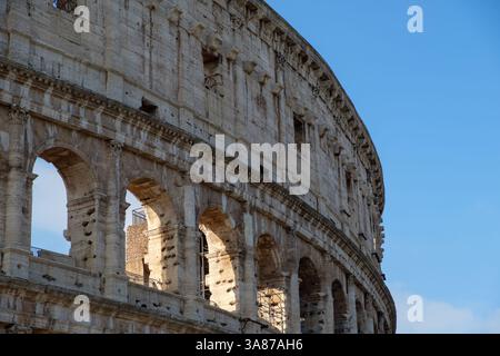 Die Außenwand des Kolosseums in Rom, Italien, steht vor einem klaren blauen Himmel. Dieses antike römische Amphitheater, ein Zeugnis der römischen Ingenieurskunst, Stockfoto