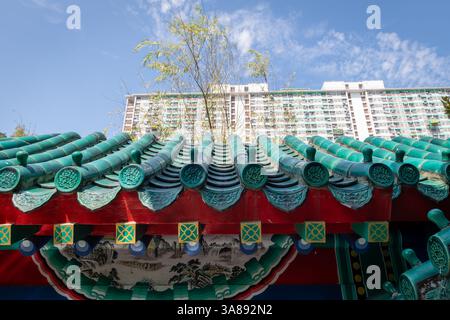 Details der traditionellen chinesischen Architektur mit farbenfrohen komplexen Elementen im Kontrast zu einem modernen Apartmentblock. Stockfoto