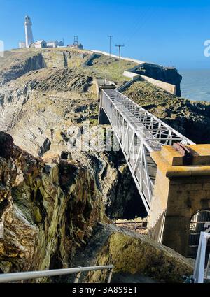 Dramatischer Blick auf den South Stack Lighthouse, Anglesey, Blick von den Stufen in Richtung Sea Stack Island überdachter Fußweg ist im Vordergrund der irischen See dahinter Stockfoto