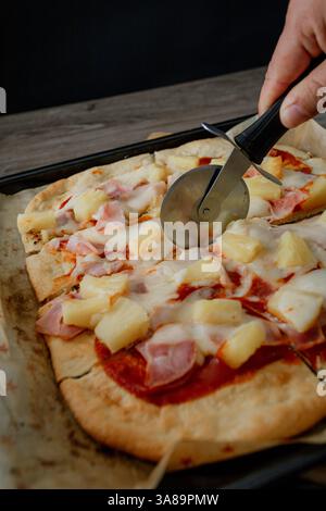 Hawaiianische Gourmet-Pizza im dunklen Stil, die ihre Zutaten in einem raffinierten Ambiente hervorhebt. Stockfoto
