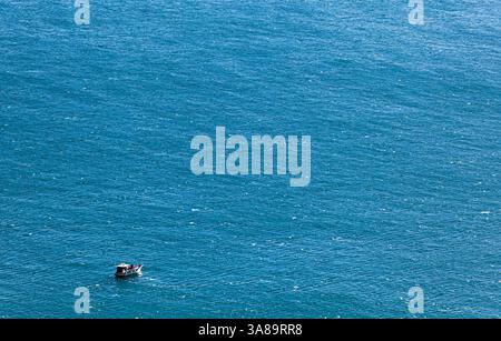 Einsames Boot in der weiten Weite des tiefblauen Meeres, aus der Luft. Perfekt für Reisethemen, Tranquility-Konzepte oder maritimen Designs. Stockfoto