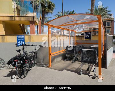 Roquetas de Mar, Almeria, Andalusien, Spanien 27. März 2025: Fahrradparkplatz und Einkaufswagen im Geschäft. Stockfoto
