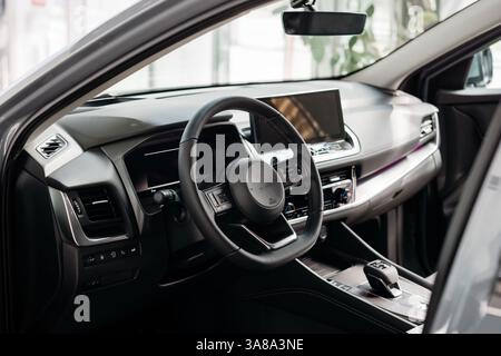 Nahaufnahme eines Autolenkrads in einem modernen Neuwagen. Der Innenraum eines stilvollen neuen Autos. Konzept für stilvolles Design, Shopping und Autoteile. Stockfoto