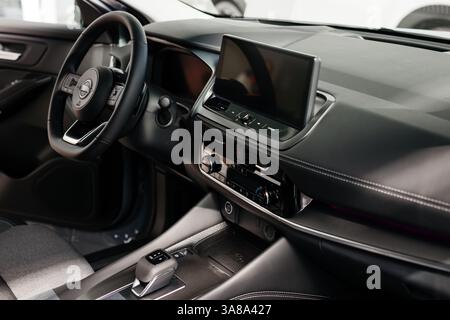Nahaufnahme eines Autolenkrads in einem modernen Neuwagen. Der Innenraum eines stilvollen neuen Autos. Konzept für stilvolles Design, Shopping und Autoteile. Stockfoto