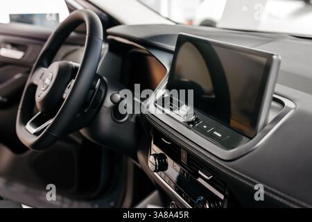 Nahaufnahme eines Autolenkrads in einem modernen Neuwagen. Der Innenraum eines stilvollen neuen Autos. Konzept für stilvolles Design, Shopping und Autoteile. Stockfoto