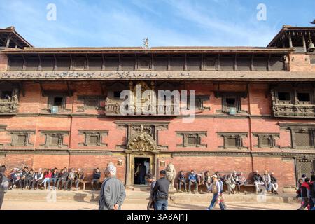 Die Menschen versammeln sich vor dem Kumari Ghar (Haus der lebenden Göttin) auf dem Kathmandu Durbar Square, Nepal, um sich auszuruhen und das tägliche Leben an diesem Ort zu beobachten. Stockfoto