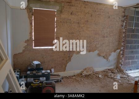 Renovierungsarbeiten werden durchgeführt: Putz wird von einer inneren Ziegelwand entfernt, wodurch die darunter liegende Struktur freigelegt wird. Stockfoto