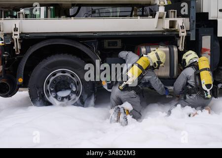 Notfallpersonal, das in Gefahrenanzügen und in sich geschlossene Atemgeräte gekleidet ist, die von Schaumstoff umgeben sind, nimmt den aus einem Lkw austretenden Dieselkraftstoff auf. Stockfoto
