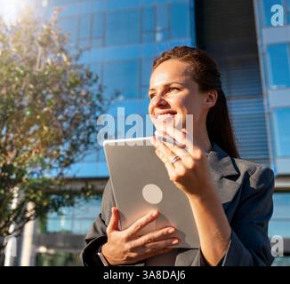 Porträt einer selbstbewussten Geschäftsführerin, die ein digitales Tablet außerhalb des Bürogebäudes hält Stockfoto