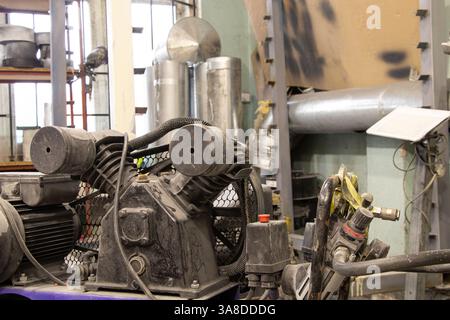 Der Kompressor befindet sich auf dem Boden in der Malerwerkstatt, die Arbeitsausrüstung befindet sich in der Werkstatt Stockfoto