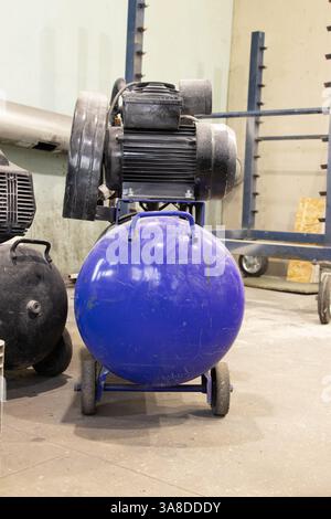 Der Kompressor befindet sich auf dem Boden in der Malerwerkstatt, die Arbeitsausrüstung befindet sich in der Werkstatt Stockfoto