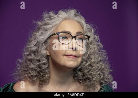 Eine schöne grauhaarige Frau in einem roten Pullover ist eine ältere Dame mit einer positiven Einstellung, die nachdenklich weg schaut und Reife und innere h symbolisiert Stockfoto