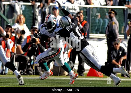 27. November 2005 Oakland, KALIFORNIEN - die Dolphins Ricky Williams #34 in Aktion läuft, als die Raiders Jarrod Cooper #40 versucht, es anzupacken. Die Miami Dolphins besiegten die Oakland Raiders 33-21 im McAfee Coliseum in Oakland, Kalifornien Stockfoto