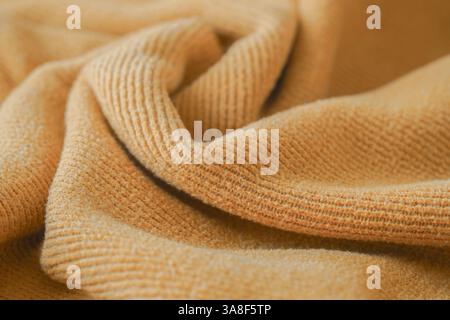 Nahaufnahme aus weichem gelbem Stoff mit gestrickter Textur, perfekt für Mode, Textildesign und gemütliche Bekleidungskonzepte. Stockfoto