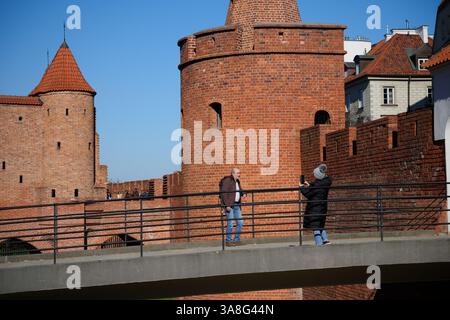 Warschau. März 2025. Ein Besucher posiert für Fotos auf der Brücke vor dem Barbican in Warschau, Polen am 28. März 2025. Quelle: Jaap Arriens/Xinhua/Alamy Live News Stockfoto