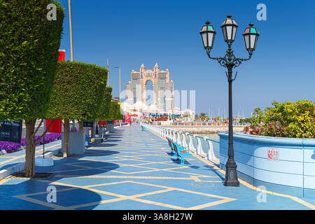 Abu Dhabi, Vereinigte Arabische Emirate - 10. Januar 2024, Panoramablick auf die Promenade mit Bäumen und Laternen, Rixos Marina Hotel im Hintergrund, tagsüber Stockfoto