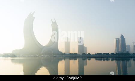 Doha, Katar [24. Februar 2025]: Ein nebeliger Morgen in Doha mit Wolkenkratzern, die teilweise im Nebel verborgen sind und eine geheimnisvolle und ruhige Stadtlandschaft schaffen. Stockfoto