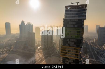 Doha, Katar – 24. Februar 2025: Ein nebeliger Morgen in Doha mit Wolkenkratzern, die teilweise im Nebel verborgen sind und eine geheimnisvolle und ruhige Stadtlandschaft schaffen. Stockfoto