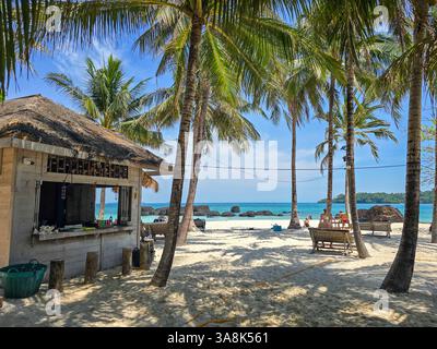 Entdecken Sie die ruhige Schönheit der Insel Koh Kham in Thailand, wo goldener Sand und sich wiegende Palmen ein perfektes tropisches Paradies bilden. Genießen Sie das kristallklare Wasser und die ruhige Atmosphäre. Stockfoto