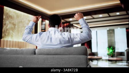 Glücklicher Mann, Der Auf Sofa Sitzt Und Im Hotel Denkt Stockfoto